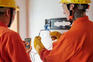 Electricians wearing protective gloves when testing electrical wires for amperage