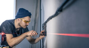 Male electrician repairing an outlet, installing an outlet using laser marking.